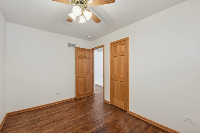 an empty room with wooden floor chandelier fan and closet area