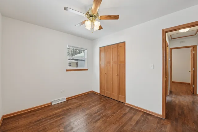 an empty room with wooden floor and a ceiling fan