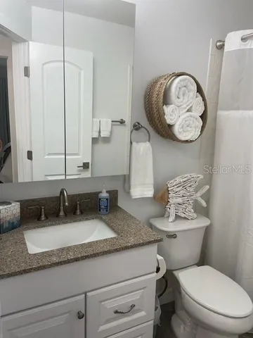 a bathroom with a granite countertop toilet sink and mirror