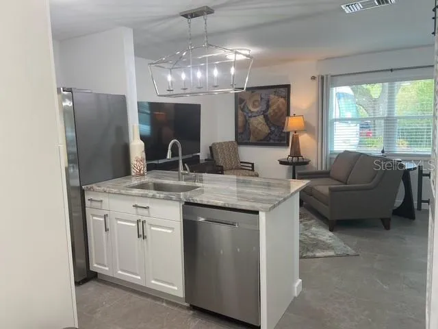 a kitchen with stainless steel appliances granite countertop a sink and a refrigerator