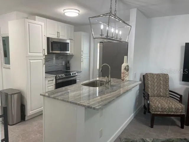 a kitchen with stainless steel appliances granite countertop a sink refrigerator and microwave