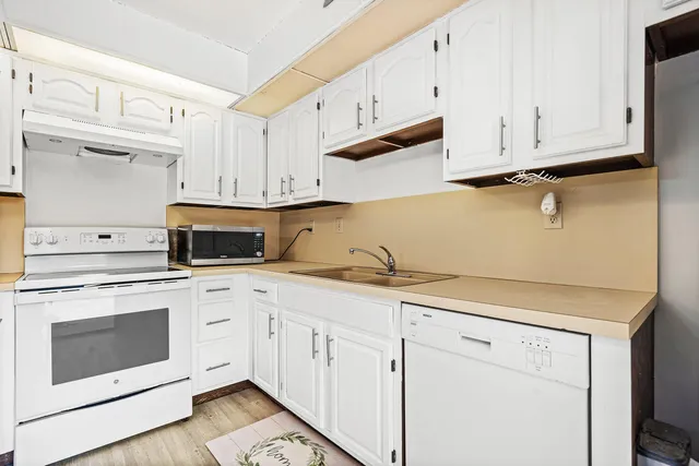 a kitchen with granite countertop white cabinets and white appliances