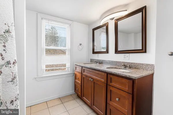 a bathroom with a granite countertop sink mirror and a window