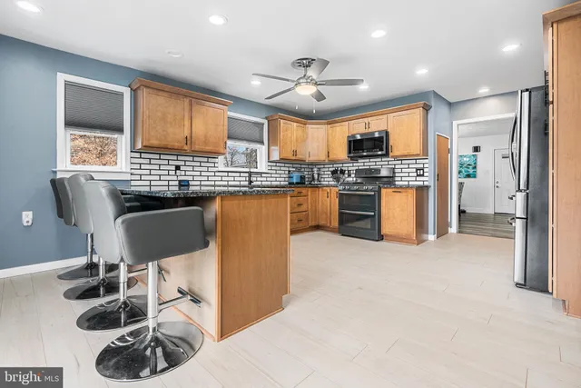 a kitchen with stainless steel appliances granite countertop a stove top oven a sink a dining table and chairs