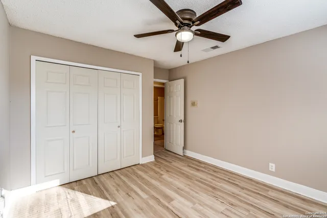 an empty room with a ceiling fan and wooden floor