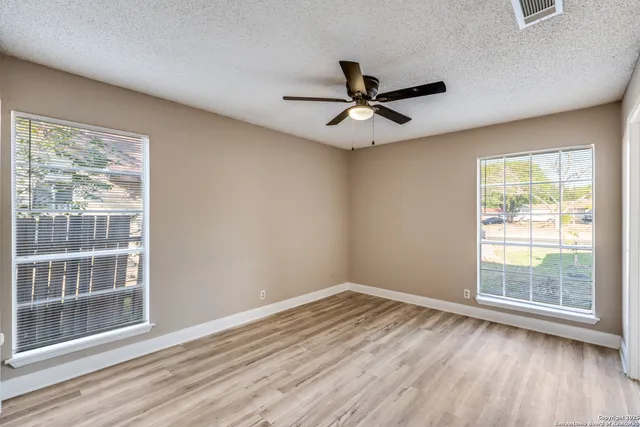 a view of empty room with wooden floor and fan