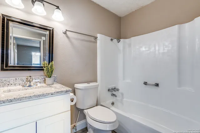 a bathroom with a granite countertop toilet a sink and a mirror