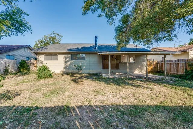 a view of a house with a yard and large tree