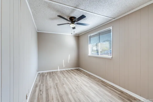 an empty room with a window and ceiling fan