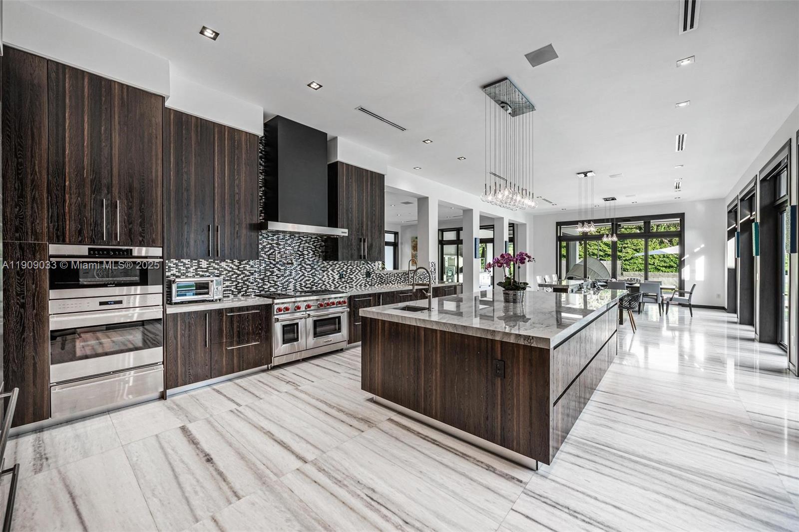 8961 Southwest 62nd Court Pinecrest, FL 33156 - Photo 12 of 72 a large kitchen with stainless steel appliances wooden floor a large counter top a stove and a refrigerator