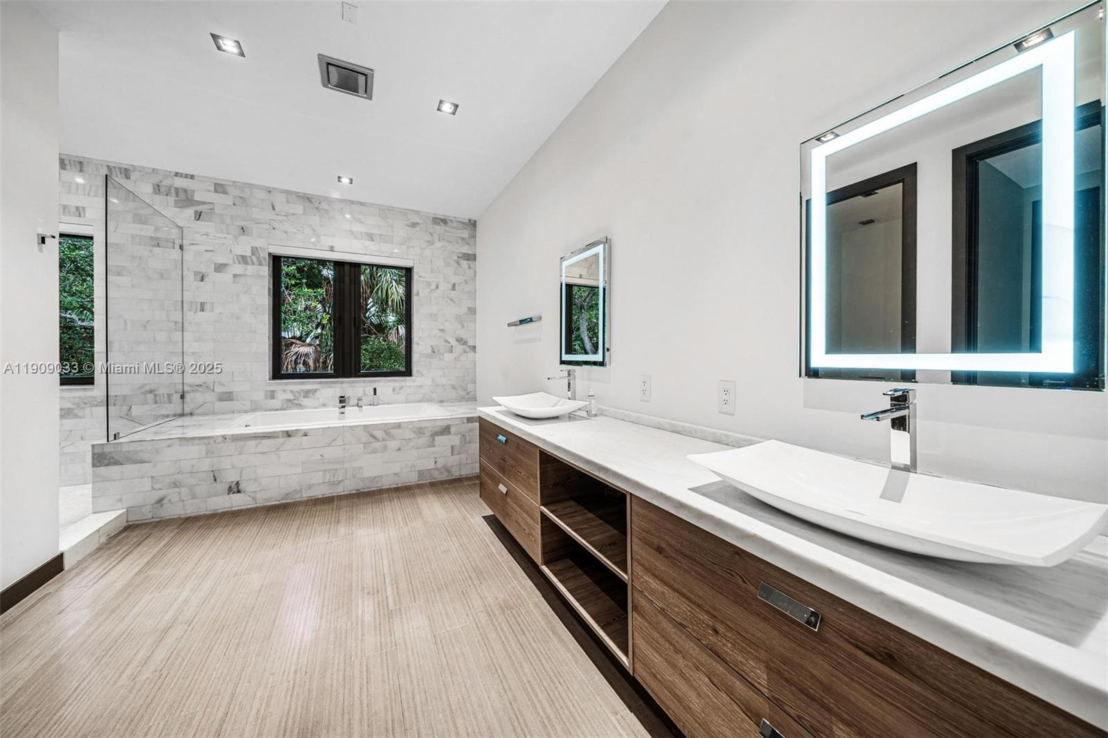 8961 Southwest 62nd Court Pinecrest, FL 33156 - Photo 46 of 72 a bathroom with a double vanity sink a mirror and a bathtub