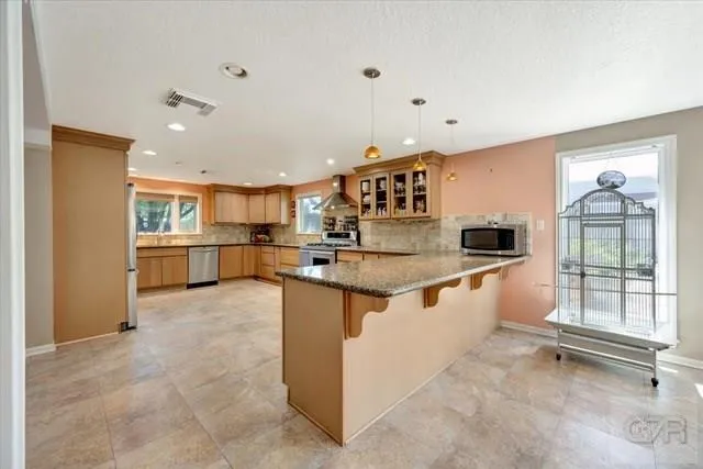 a kitchen with stainless steel appliances granite countertop a refrigerator and a stove top oven