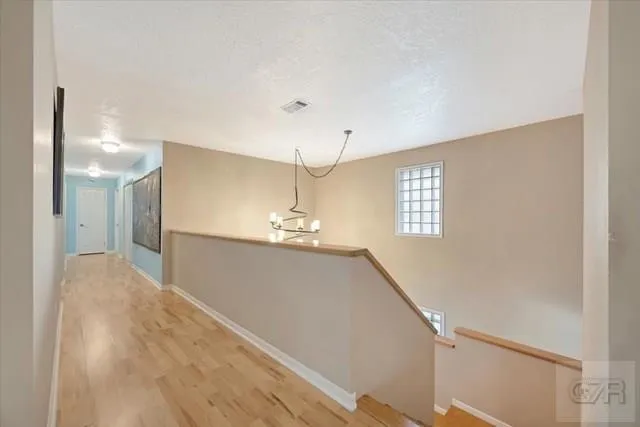a view of a hallway with window and chandelier