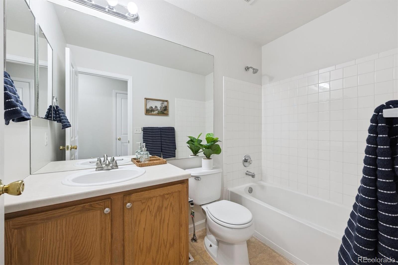 5241 Helena Street Denver, CO 80239 - Photo 17 of 28 a bathroom with a sink a toilet a mirror a vanity and shower