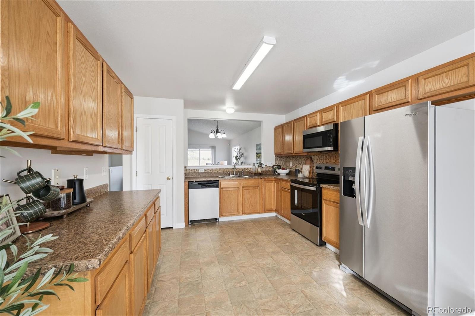 5241 Helena Street Denver, CO 80239 - Photo 6 of 28 a kitchen with granite countertop a refrigerator a sink a stove top oven and cabinets