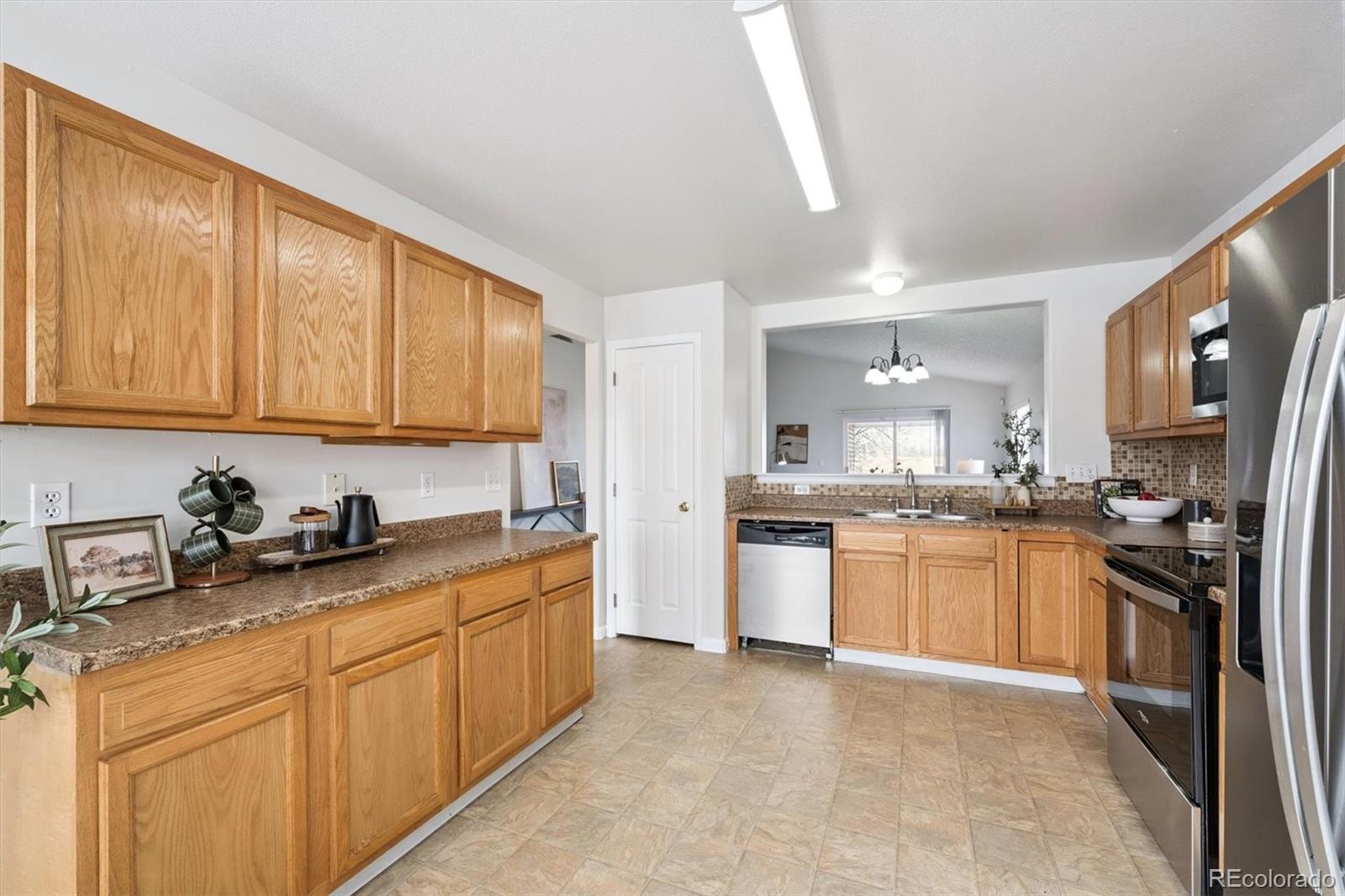 5241 Helena Street Denver, CO 80239 - Photo 7 of 28 a kitchen with stainless steel appliances granite countertop a sink stove and refrigerator