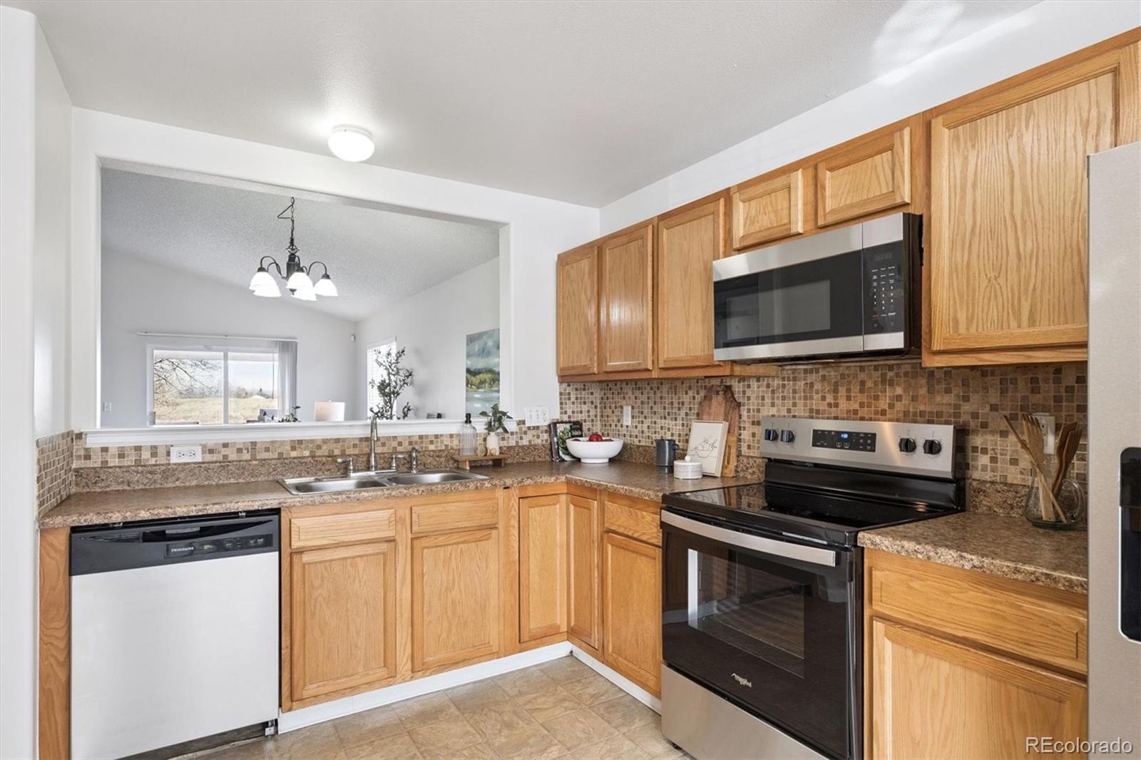 5241 Helena Street Denver, CO 80239 - Photo 8 of 28 a kitchen with stainless steel appliances granite countertop a stove top oven a sink dishwasher and microwave oven with cabinets