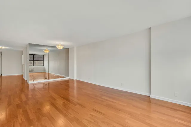 a view of empty room with kitchen and wooden floor