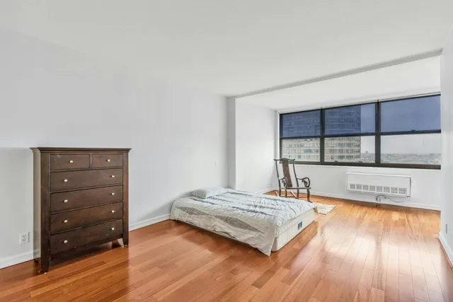 a view of a bedroom with wooden floor and window