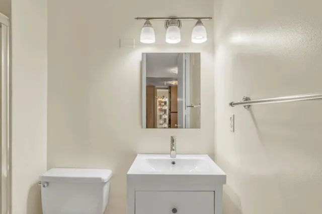 a bathroom with a toilet a sink a mirror and vanity