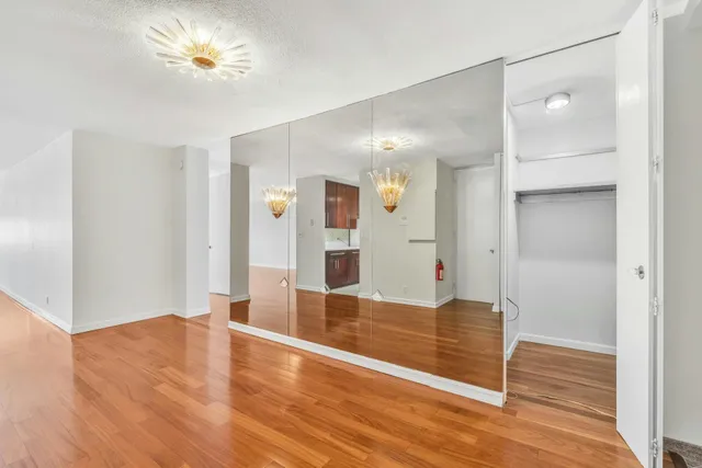 a view of empty room with wooden floor and fan