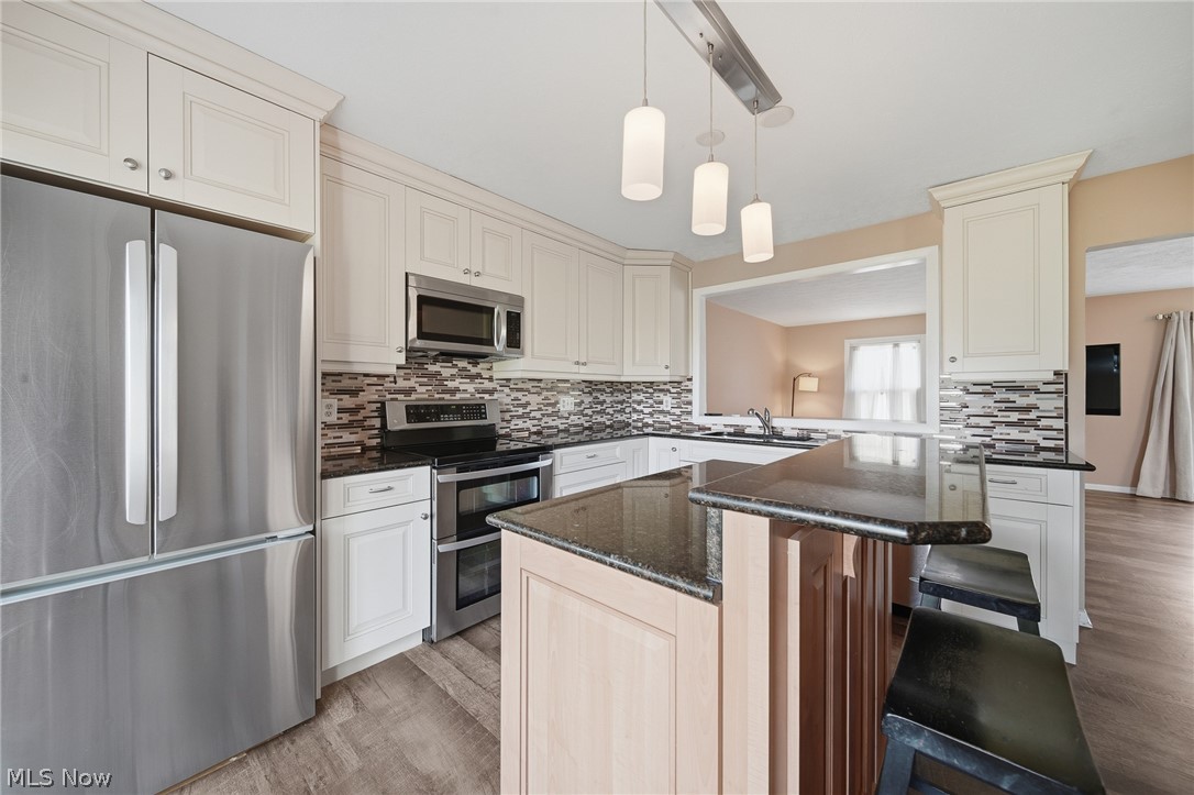 824 South Chillicothe Road, Unit 2 Aurora, OH 44202 - Photo 3 of 42 Kitchen featuring white cabinetry, dark countertops, a mosaic tile backsplash, stainless steel appliances, and wood-finish flooring