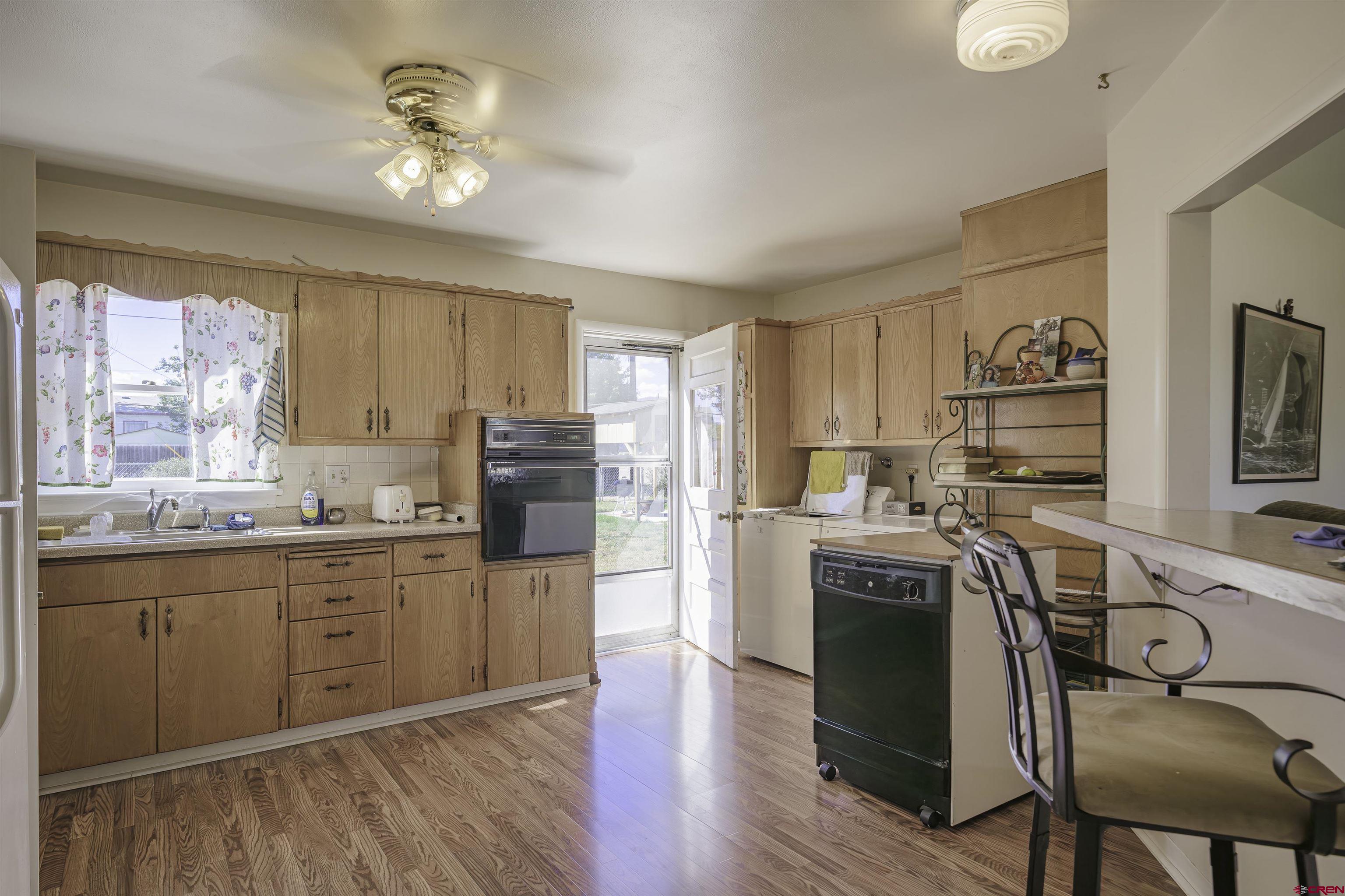 1002 East 2nd Street Florence, CO 81226 - Photo 11 of 44 a kitchen with stainless steel appliances granite countertop a refrigerator a stove a sink dishwasher and white cabinets with wooden floor