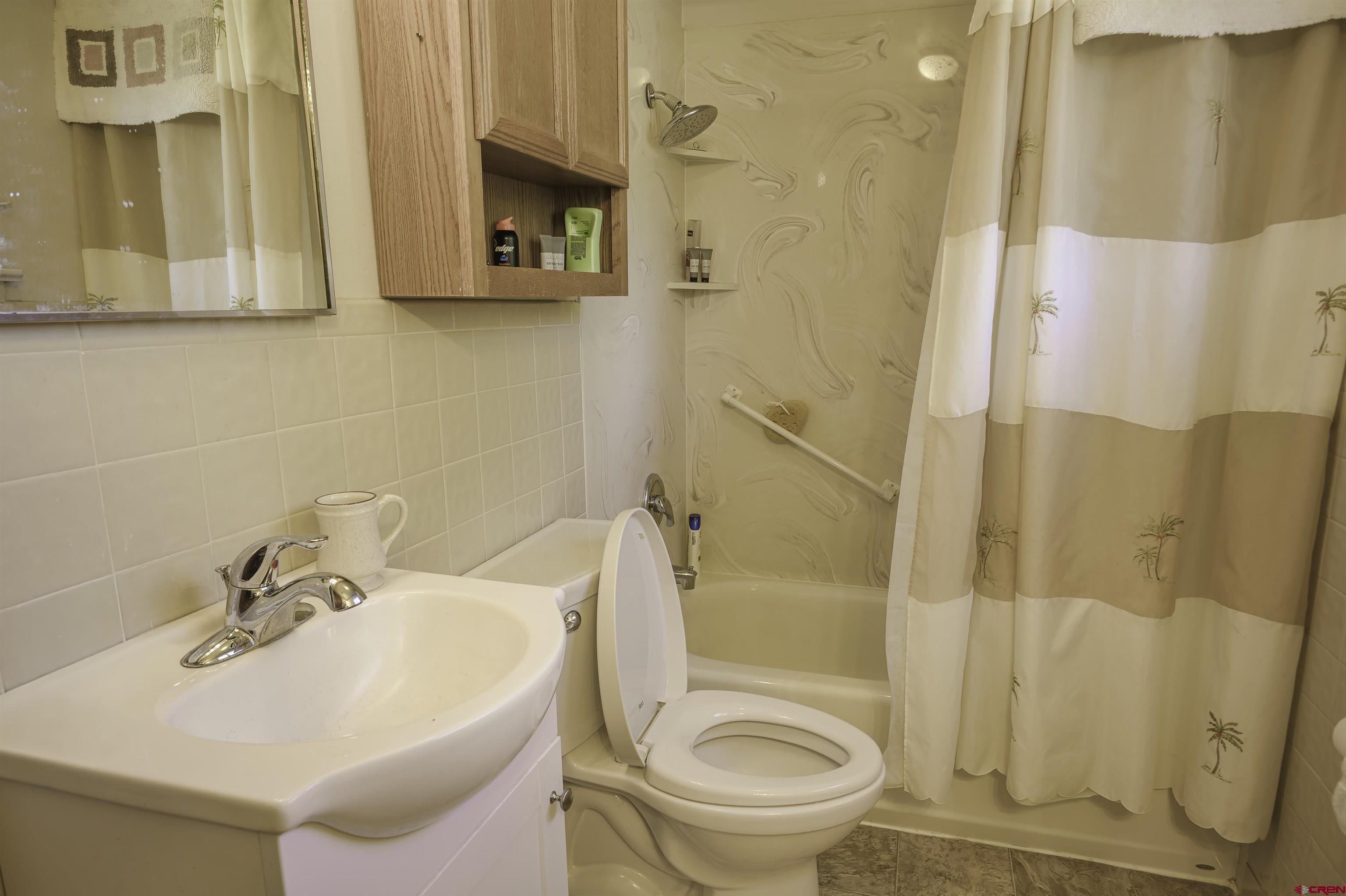 1002 East 2nd Street Florence, CO 81226 - Photo 20 of 44 a bathroom with a sink a toilet and shower curtain