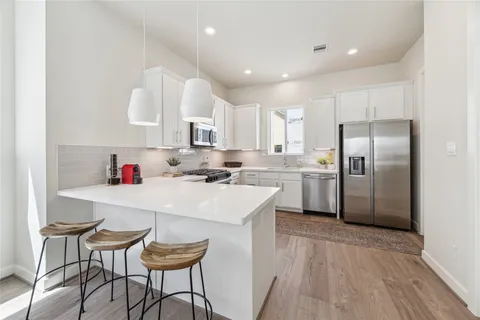 a kitchen with stainless steel appliances a table chairs refrigerator and cabinets