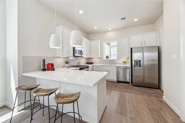 a kitchen with stainless steel appliances a table chairs refrigerator and cabinets