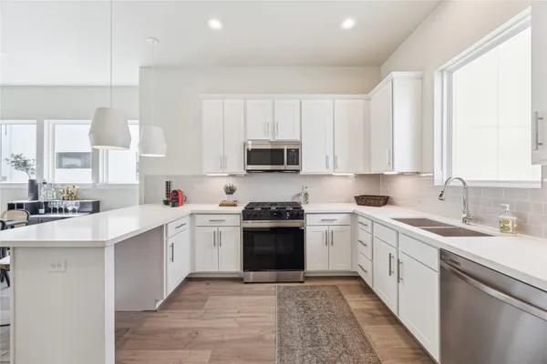 a large white kitchen with stainless steel appliances granite countertop a stove a sink and white cabinets