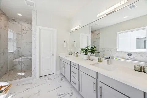 a bathroom with a double vanity sink mirror and shower