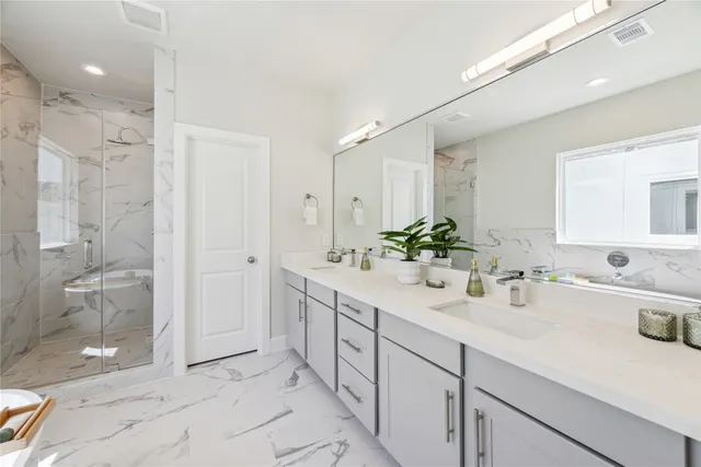 a bathroom with a double vanity sink mirror and shower