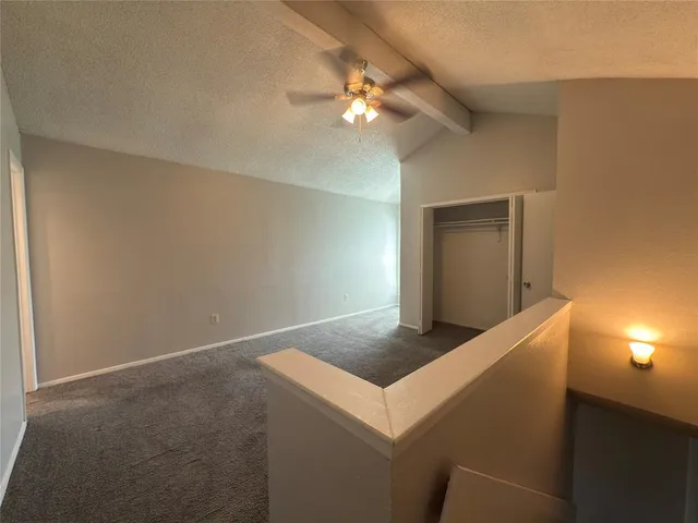 a view of an empty room and chandelier fan