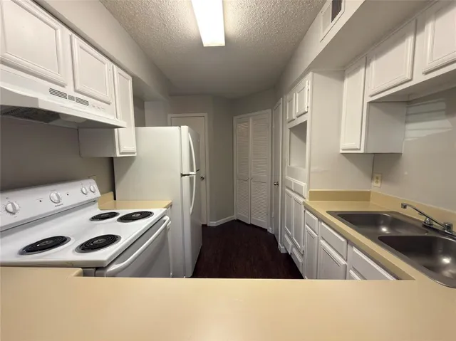 a kitchen that has a sink a stove and a refrigerator