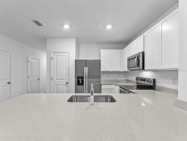 a kitchen with stainless steel appliances a refrigerator a sink a stove a microwave and cabinets