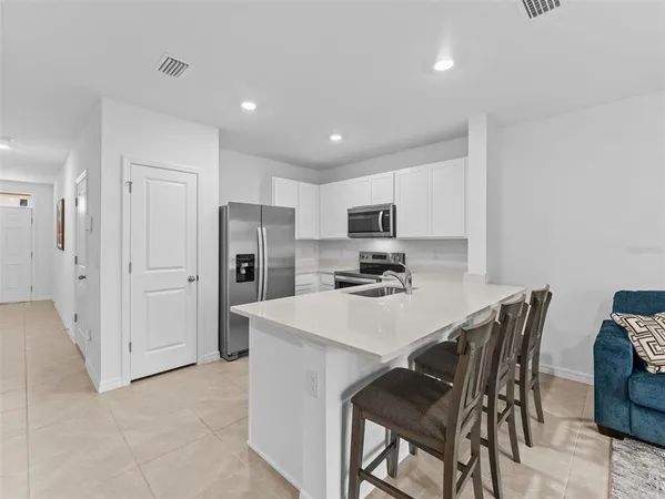 a kitchen with stainless steel appliances a table chairs refrigerator and a refrigerator