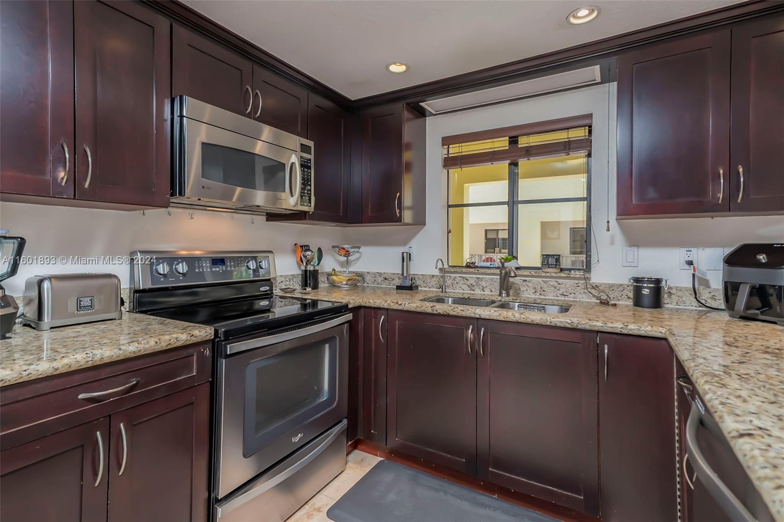 3204 Bird Avenue, Unit 109 Miami, FL 33133 - Photo 18 of 67 a kitchen with granite countertop wooden cabinets stainless steel appliances a window and a sink