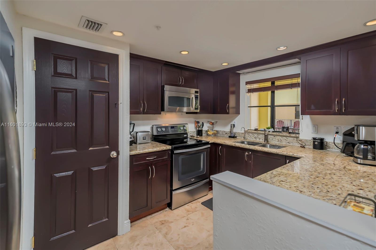 3204 Bird Avenue, Unit 109 Miami, FL 33133 - Photo 19 of 67 a kitchen with granite countertop stainless steel appliances and wooden cabinets