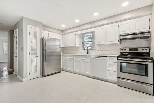 a kitchen with white cabinets and stainless steel appliances
