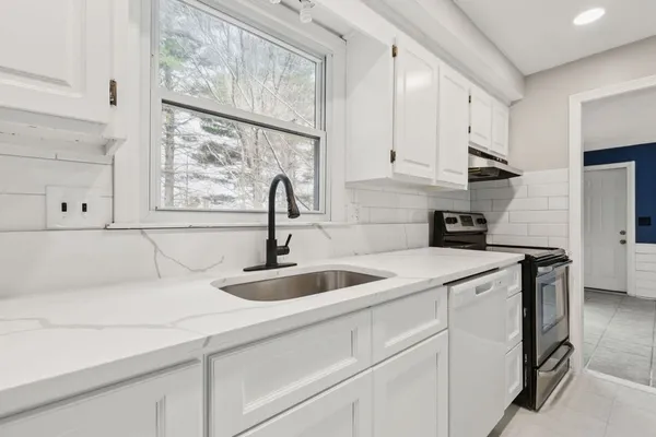 a kitchen with stainless steel appliances granite countertop a sink and a white cabinets