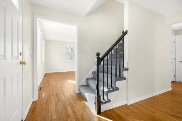 a view of a hallway with wooden floor and staircase
