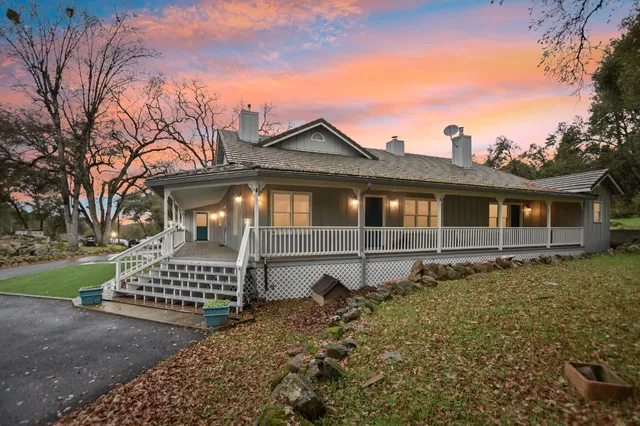 a front view of a house with a garden and trees