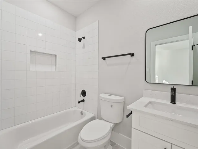 a bathroom with a toilet sink a mirror a vanity and bathtub