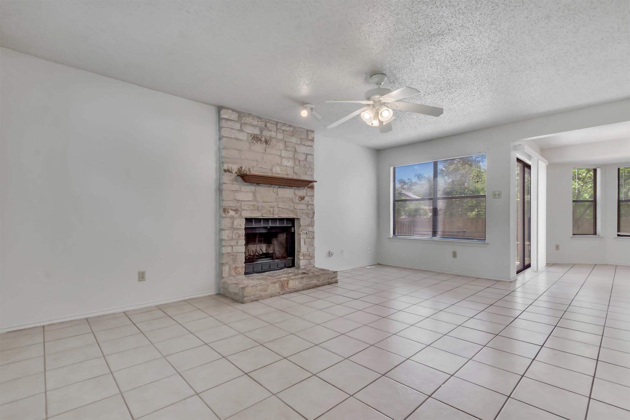 7802 Topawa Cove, Unit B Austin, TX 78729 - Photo 6 of 32 A spacious living area with tile flooring and a focal stone fireplace awaits new memories.