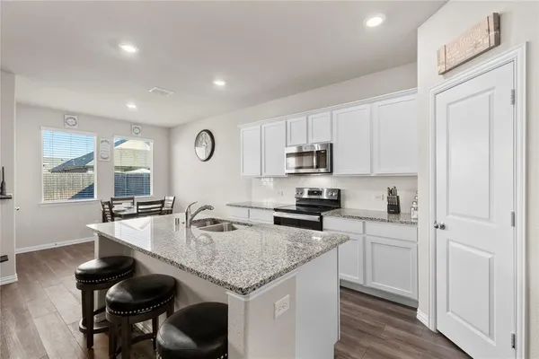 a kitchen with stainless steel appliances granite countertop a sink a stove and cabinets