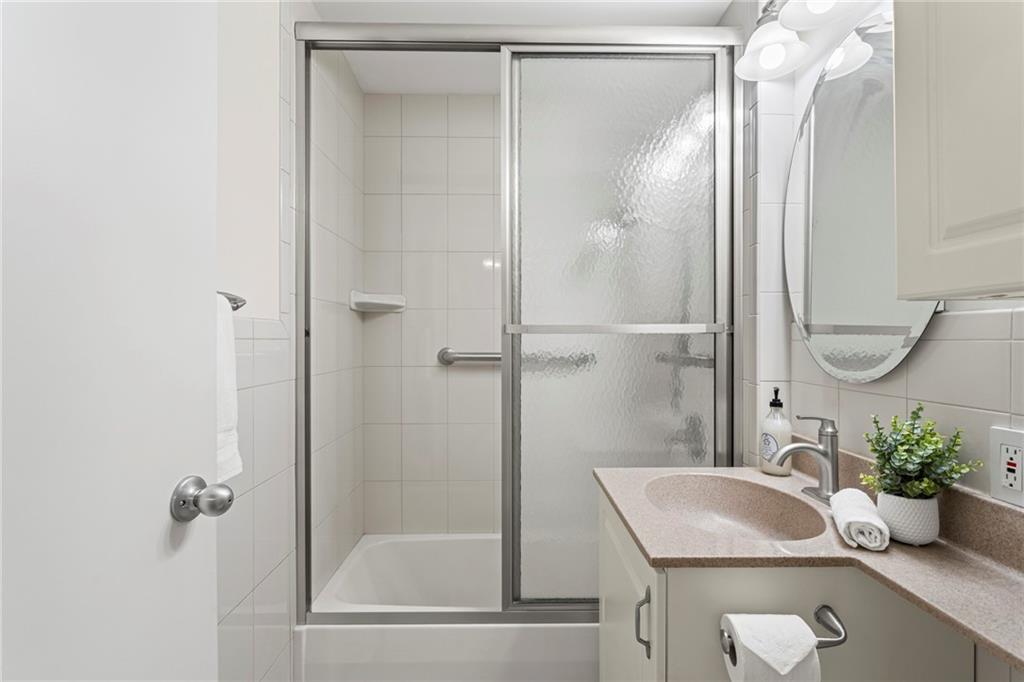 4601 Fifth Avenue, Unit 525 Pittsburgh, PA 15213 - Photo 18 of 35 a bathroom with a granite countertop sink a shower and a mirror