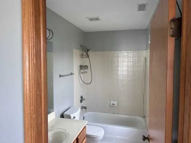 a bathroom with a granite countertop bathtub shower sink and toilet