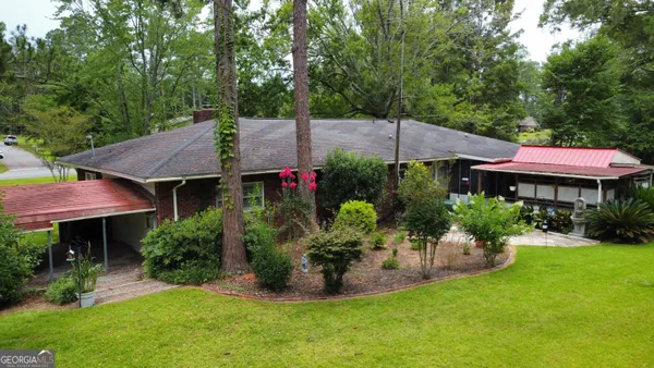 a view of a backyard with table and chairs and potted plants and large trees