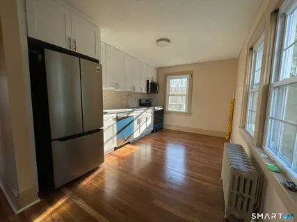 a kitchen with a refrigerator a stove top oven and wooden floor
